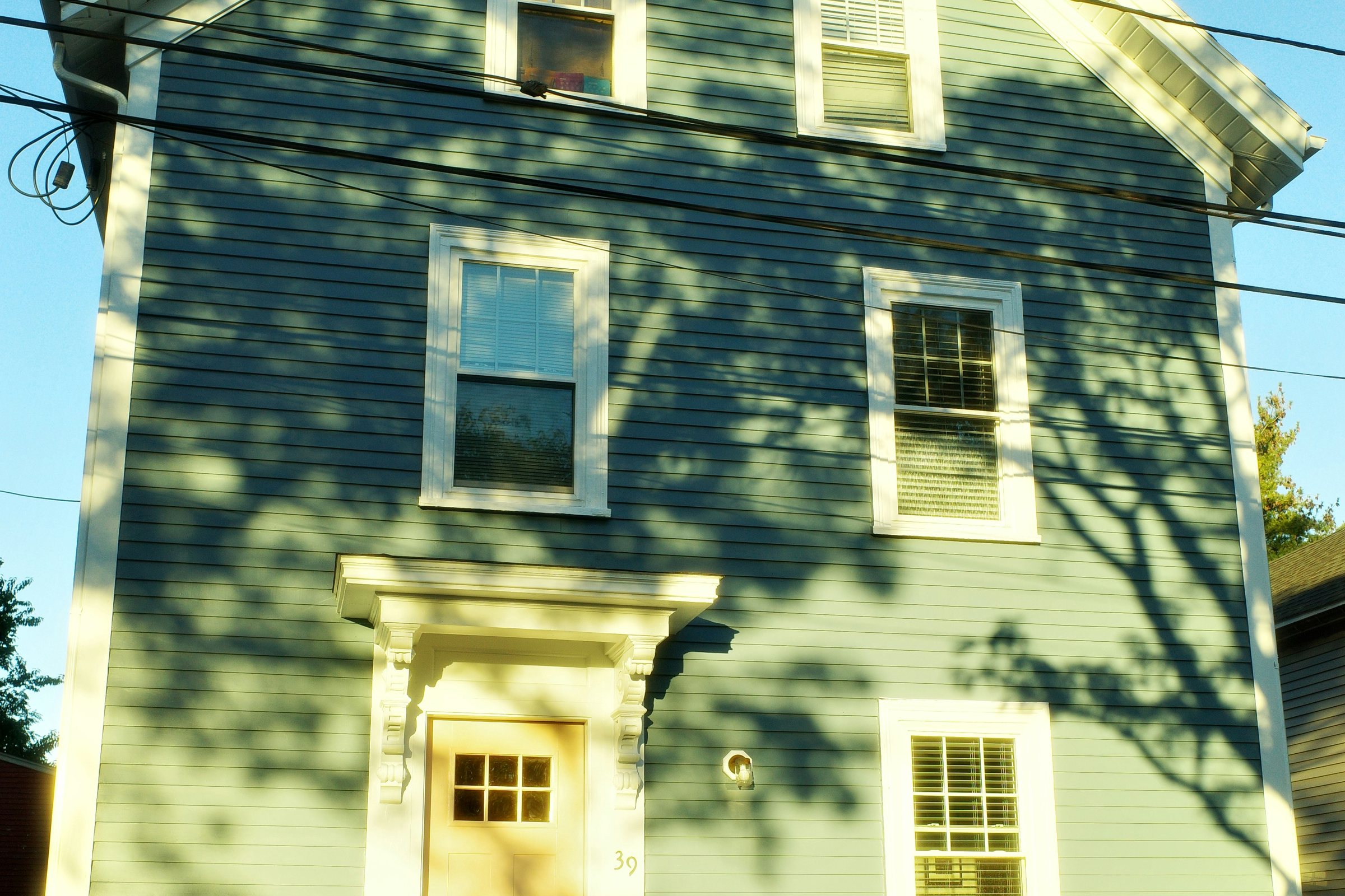 A light blue clapboard house in late sun